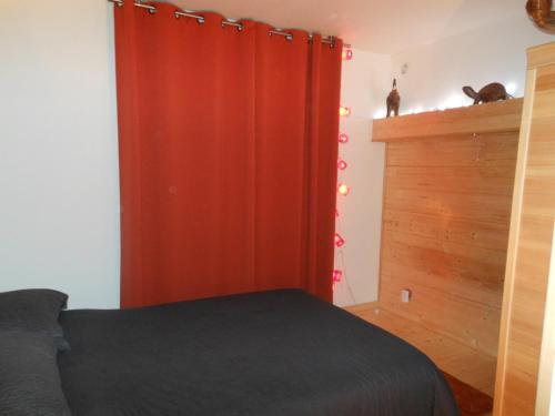 1 dormitorio con cama y cortina roja en Les Berges de l'Ô, en Saint-Nicolas-de-Port