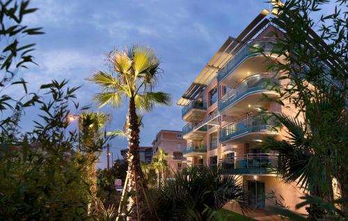 a tall building with a palm tree in front of it at Villa Romana Fréjus in Fréjus