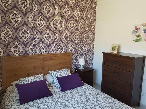 a bedroom with a bed with purple pillows and a wallpaper at Casa Kiko in Playa de Santiago
