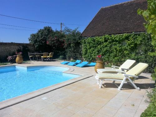 a swimming pool with two lounge chairs and a table at Tourterelle, à proximité de Auxerre et Chablis in Hauterive