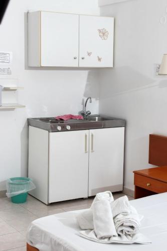 a kitchen with a sink and white cabinets at Elarin studios & apartments in Faliraki