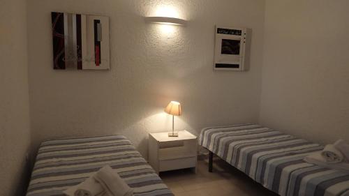 two beds in a room with a lamp on a table at Résidence les Hameaux de Bocca del Oro in Porto-Vecchio
