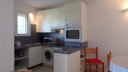 a kitchen with white cabinets and a washing machine at Résidence les Hameaux de Bocca del Oro in Porto-Vecchio
