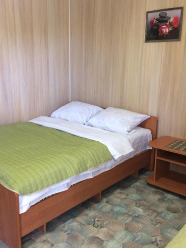 ein Bett mit weißer Bettwäsche und einer grünen Decke in der Unterkunft Дом семейного отдыха in Karolino-Buhas
