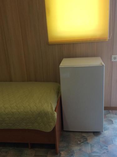 Kleines Zimmer mit einem kleinen Kühlschrank und einem Bett. in der Unterkunft Дом семейного отдыха in Karolino-Buhas