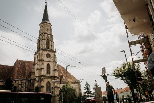 an old church with a clock tower on a street at Alandala by The Center in Cluj-Napoca