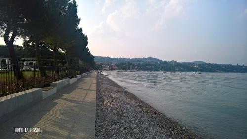 a body of water with a person walking on the shore at Hotel La Bussola in Padenghe sul Garda