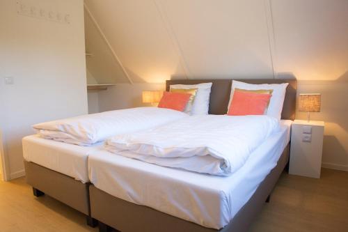 a large bed with white sheets and orange pillows at De Koolmees met privé Hottub en Sauna 5-persoons in Lievelde