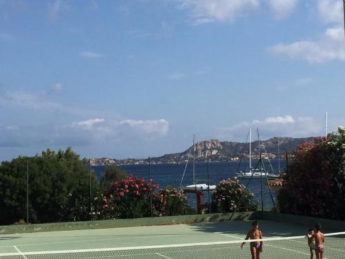 two men playing tennis on a tennis court near the water at Case sul mare in Palau