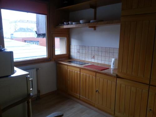 eine kleine Küche mit Holzschränken und einem Fenster in der Unterkunft Szekszárd Apartman in Szekszárd