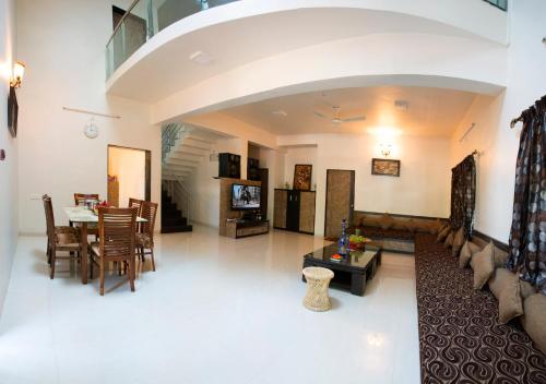 uma grande sala de estar com mesa e cadeiras em Aneesha Villa em Mahabaleshwar