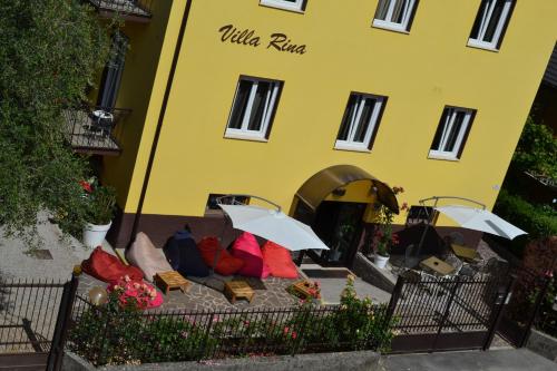 a yellow building with a couch with umbrellas in front of it at Hotel Villa Rina in Riva del Garda
