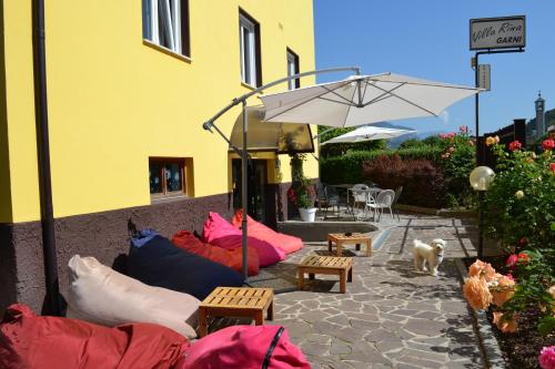 a patio with a bunch of pillows and an umbrella at Hotel Villa Rina in Riva del Garda
