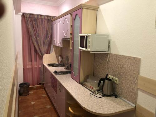a small kitchen with purple cabinets and a microwave at Дом у Ильича г Ялта поселок Гаспра ул Маратовская 16 с 2 санузлами in Gaspra