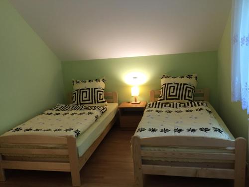 2 camas en una habitación pequeña con una lámpara en una mesa en Holiday house EWA en Meszna Opacka
