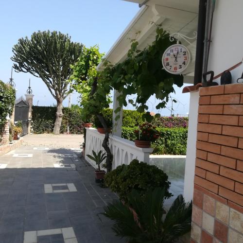 a clock on the side of a house with plants at SANTA VENERE Apartments "PARCHEGGIO interno MOTO-AUTO" Ricarica auto Elettriche in Tropea
