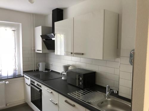 eine Küche mit weißen Schränken und einer schwarzen Arbeitsplatte in der Unterkunft Apartment Hannover / Messe in Hannover