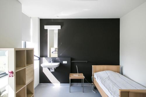 een slaapkamer met een zwarte muur, een wastafel en een bed bij De Kleppe in Everbeek