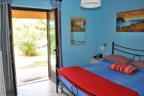 Dormitorio azul con cama y puerta corredera de cristal en Appartamenti Acacia e Gardenia en Marina di Campo