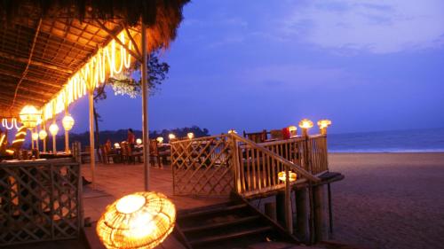 a restaurant on the beach at night with lights at The LaLiT Golf & Spa Resort Goa in Canacona