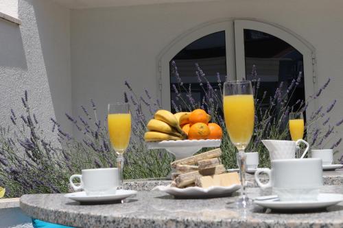 a table with a bowl of fruit and two glasses of orange juice at Hotel Bavaria Trogir in Trogir