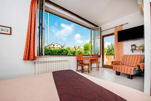 um quarto com uma grande janela e uma mesa com uma cadeira em Vila Dolores em Rovinj
