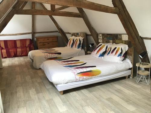 two beds in a attic room with wooden floors at Tatiana Buirette in Samer