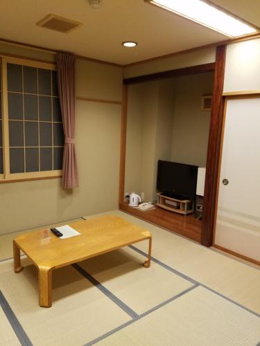 a living room with a table and a flat screen tv at Hakuba Hotel Hana-no-Sato in Hakuba
