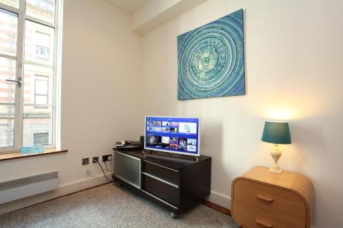 a room with a tv and a table with a lamp at Park Row Apartments in Leeds