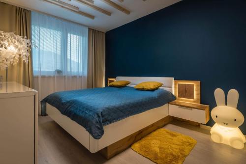 a bedroom with a bed with a blue wall at Apartmanica Triangel 103 in Donovaly