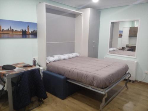een slaapkamer met een bed, een bureau en een spiegel bij Apartamentos Corazón del Húmedo in León