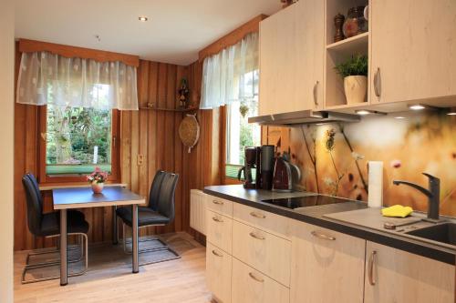 a kitchen with a sink and a table with chairs at Ferienhaus Erzgebirge "An der Trebe" mit Kamin und Sauna in Neuhausen