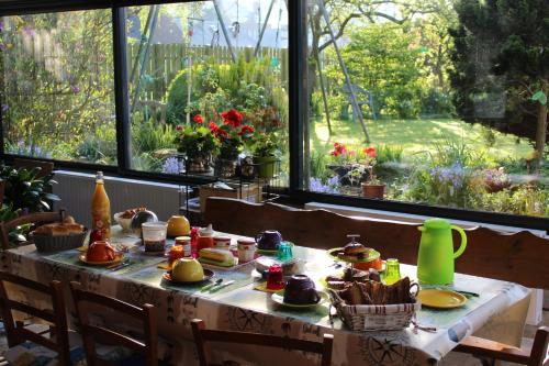 a table with food and flowers in a room with a window at Chez Catherine - Chaumière Normande in Theuville-aux-Maillots