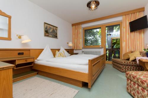 a hotel room with a bed and a couch at Landhotel Die Waldschänke in Kochel
