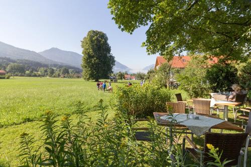 a garden with a table and chairs and a field at Landhotel Die Waldschänke in Kochel