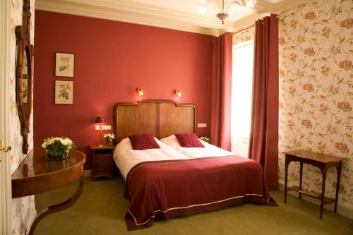 a bedroom with a bed and a red wall at Stadspaleis Hotel & Restaurant OldRuitenborgh in Vollenhove