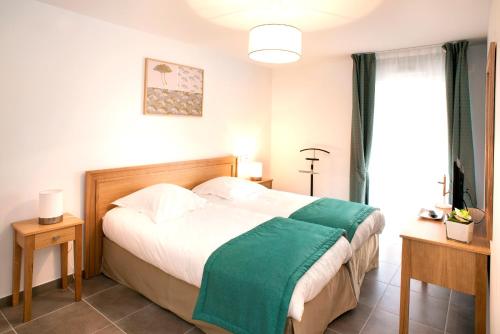 a bedroom with a bed with a green blanket on it at Domitys La Palombine in Saint-Raphaël