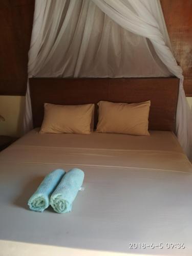 a bed with two towels sitting on top of it at Cnunk Bungalow in Gili Meno