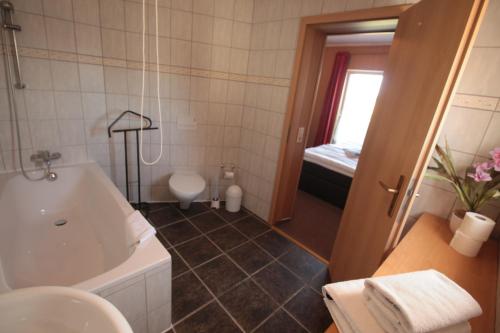 a bathroom with a tub and a toilet and a sink at Lindenhof Liepgarten - Pension & Gaststätte in Ueckermünde