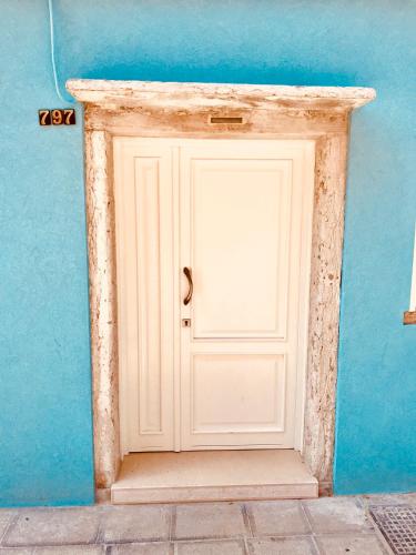 a white door in front of a blue wall at Barbara’s rooms in Chioggia