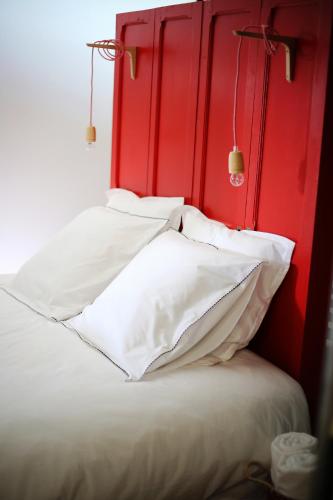 a bed with a red headboard and white pillows at equihome in Écommoy