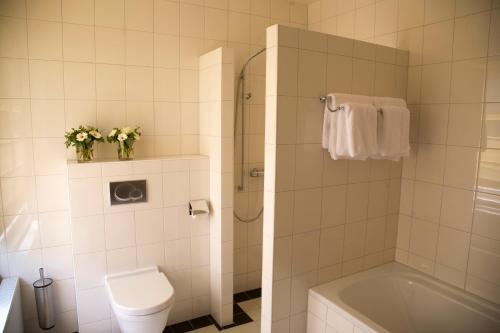 een badkamer met een toilet, een wastafel en een bad bij Stadspaleis Hotel & Restaurant OldRuitenborgh in Vollenhove