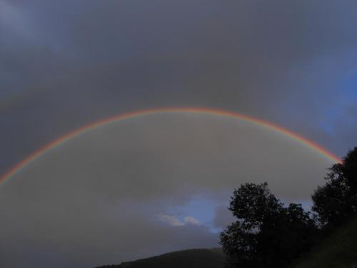 a rainbow in a cloudy sky with trees at Agriturismo La Casa Nei Boschi in Colderù