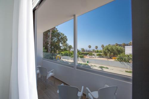 a room with a large window and a table and chairs at Stratovarius Nissi Rooms in Ayia Napa