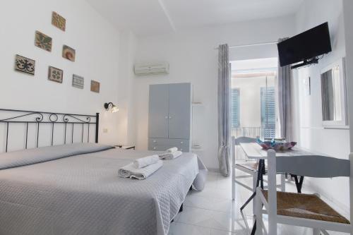 a white bedroom with two beds and a desk at Lo Nardo Accommodation in Lipari