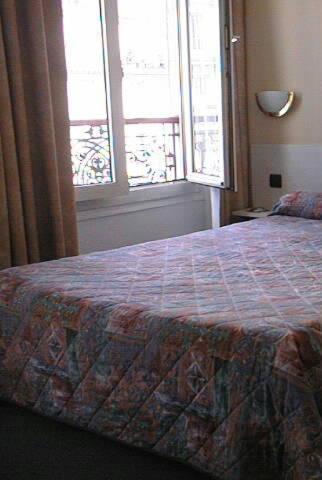 a bedroom with a bed and two windows at Hotel Ferney République in Paris
