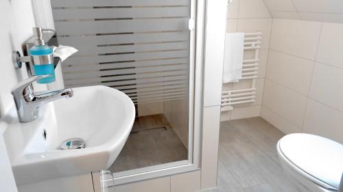 a white bathroom with a sink and a toilet at Hotel Stadt Soltau in Soltau