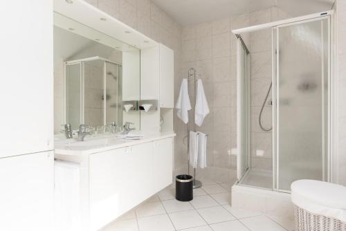 ein weißes Bad mit einer Dusche und einem Waschbecken in der Unterkunft Lovely Guesthouse Lier in Lint