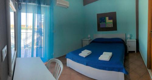 Dormitorio azul con cama, mesa y ventana en La Casa Gialla, en Trabia