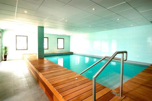 a large swimming pool with a wooden ramp in a building at Domitys Les Deux Lacs in Rumilly